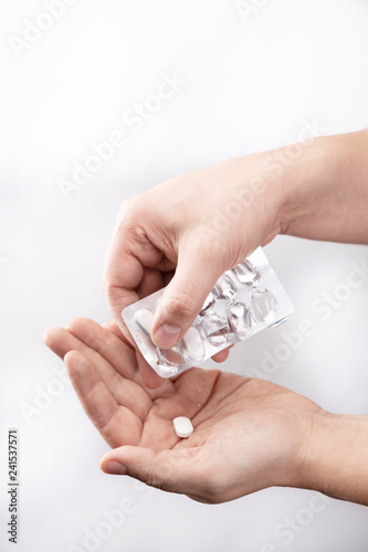 Suplementy i witaminy w tabletce. Mężczyzna wyciska tabletkę na dłoń.