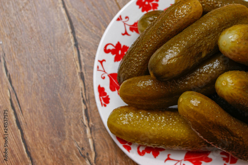 Pickled cucumber in a porcelain plate on vintage wooden table