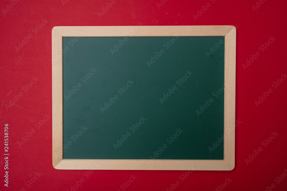 Green blank empty chalkboard with wooden frame, red wall background, copy space Green blank empty chalkboard with wooden frame, red wall background, copy space