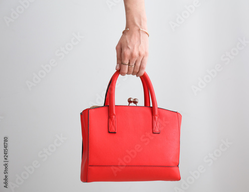 Female hand with stylish bag on light background