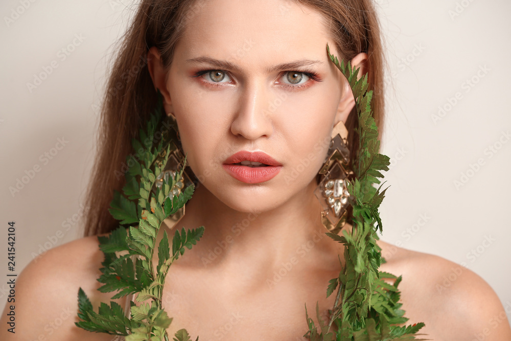 Portrait of beautiful woman with green fern leaves on light background Portrait of beautiful woman with green fern leaves on light background