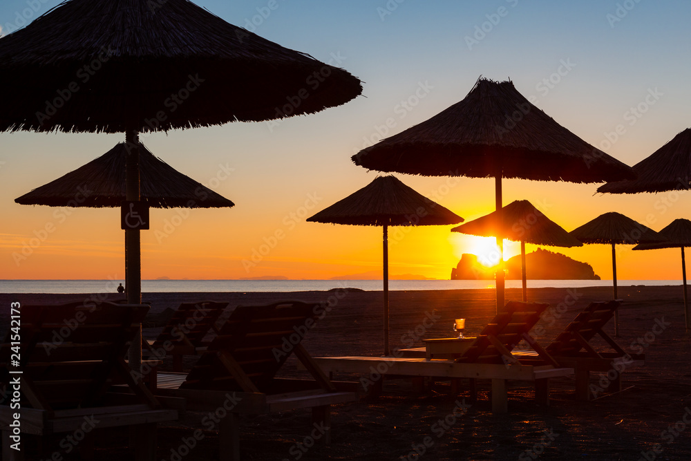 Sunset in holiday resort with umbrellas on beach