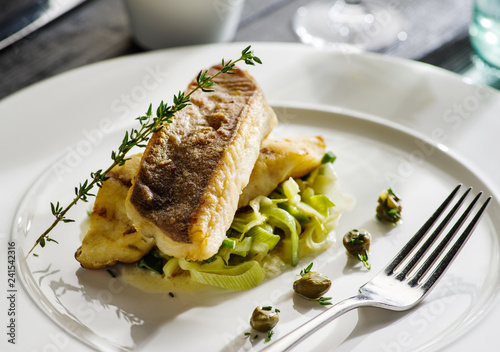 Fillet of halibut on a pillow of stewed leeks on the white plate. photo