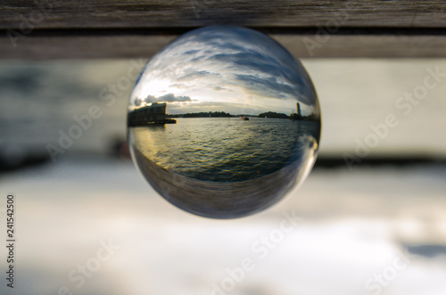 Dramatic cloudy sky at oceanside in clear crystal glass ball.