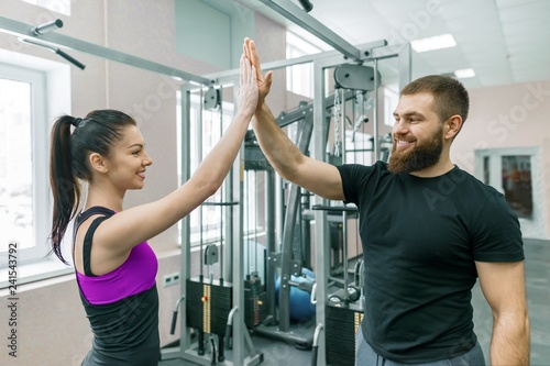 Young smiling fitness woman giving high-five to personal trainer. Fitness, sport, training, people, healthy lifestyle concept