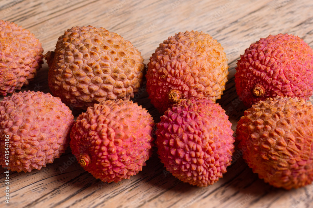 Raw pink and orange lychees on a wooden background Raw pink and orange lychees on a wooden background
