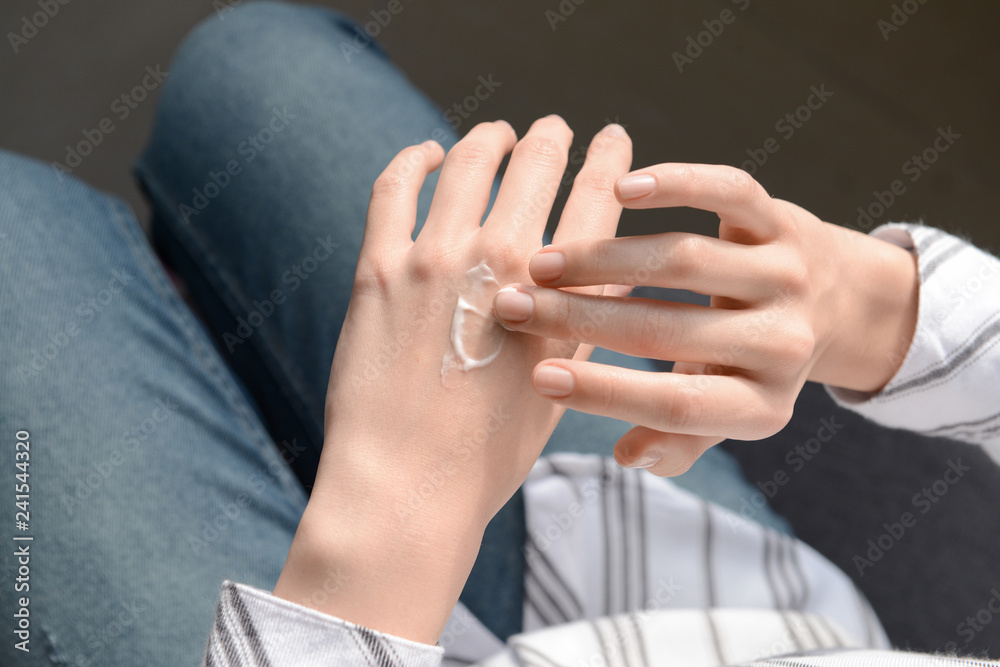 Fototapeta premium Young woman applying hand cream, closeup