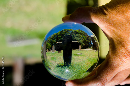 Black cross stone cemetery photography in clear crystal glass ball.
