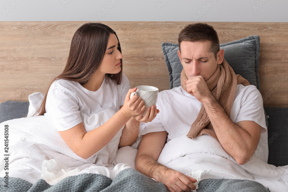 Woman taking care of her husband ill with flu at home Woman taking care of her husband ill with flu at home