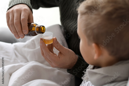 Father giving medicine to h...