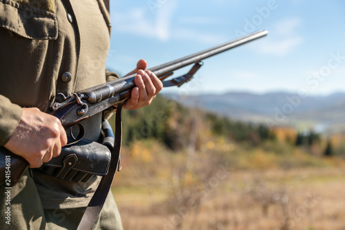 Guard on the environment at work, horizontal double-barreled shotgun in the hands, in the mountains