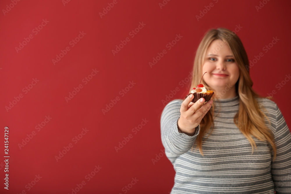 Beautiful plus size girl with sweet cake on color background. Concept of body positivity Beautiful plus size girl with sweet cake on color background. Concept of body positivity