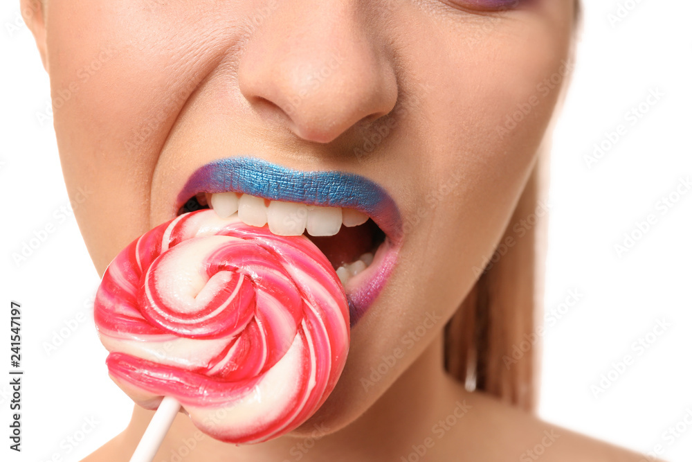 Beautiful young woman with unusual makeup and sweet lollipop on white background, closeup