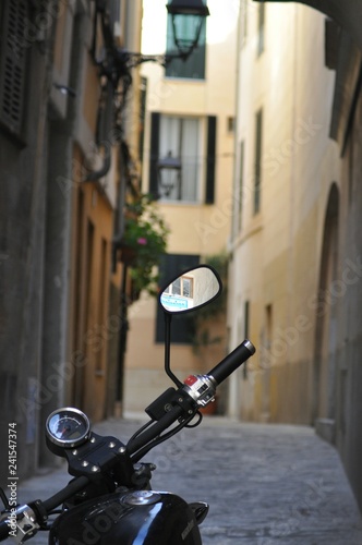 A reflection in a motorcycle's mirror, standing on a small street in Spain.