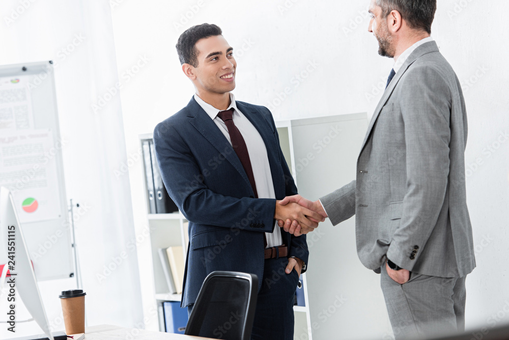 professional businessman in formal wear shaking hands and smiling each other in office professional businessman in formal wear shaking hands and smiling each other in office
