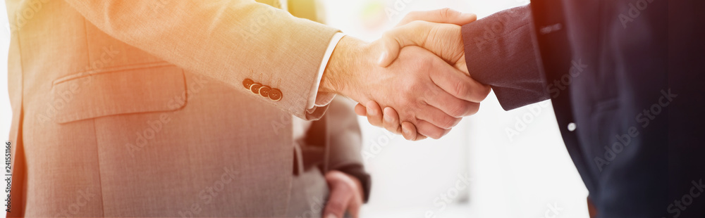 close-up partial view of businessmen in formal wear shaking hands in office close-up partial view of businessmen in formal wear shaking hands in office