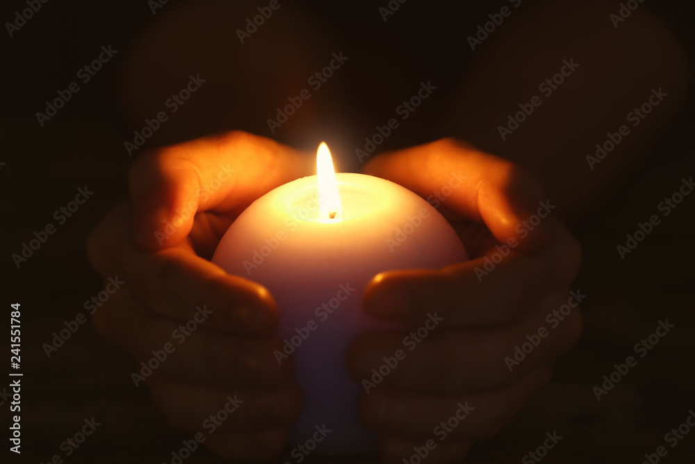 Female hands with burning candle in darkness Female hands with burning candle in darkness