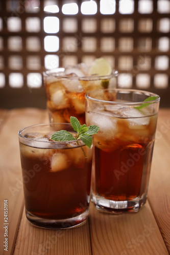 Glasses of tasty cold cola drink on wooden table