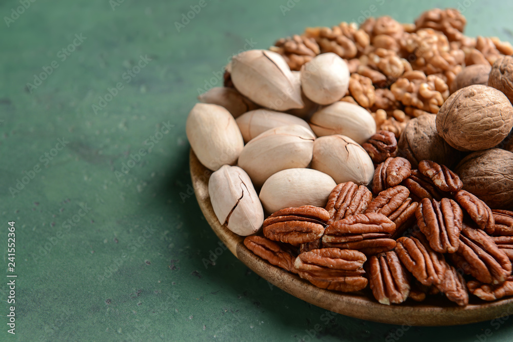 Plate with walnut and pecan nuts on color background Plate with walnut and pecan nuts on color background