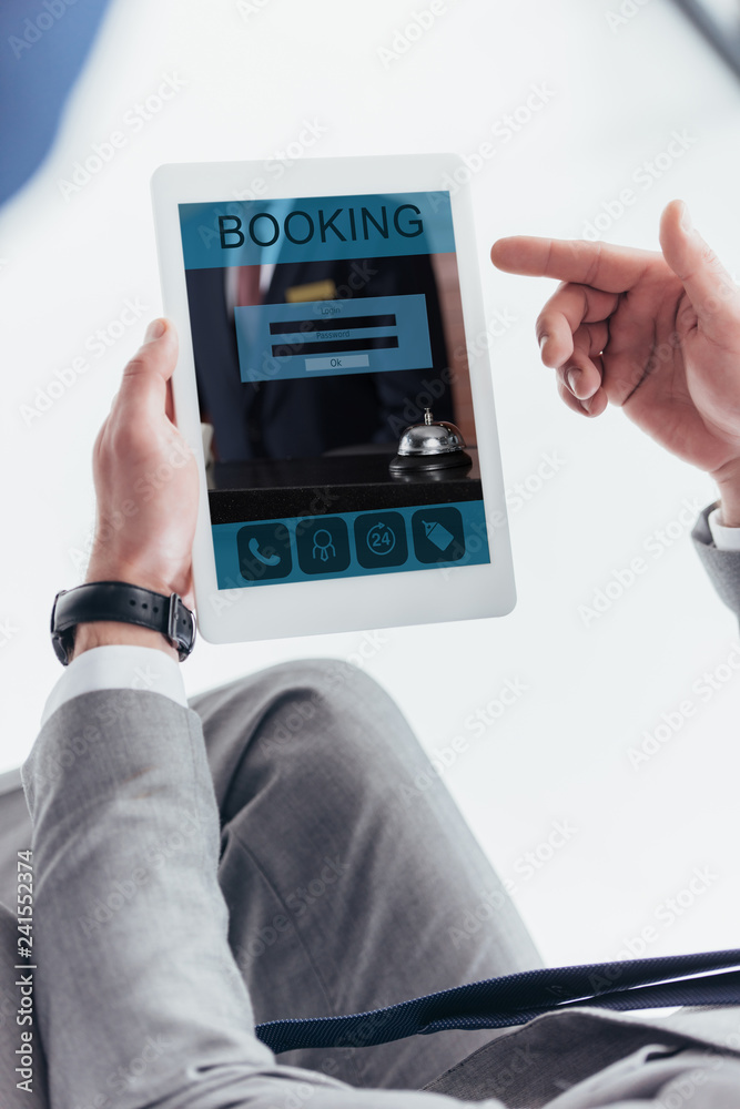 partial view of businessman using digital tablet with booking application on screen partial view of businessman using digital tablet with booking application on screen