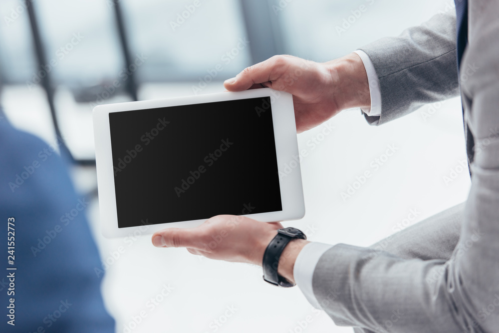 partial view of businessman holding digital tablet with blank screen partial view of businessman holding digital tablet with blank screen