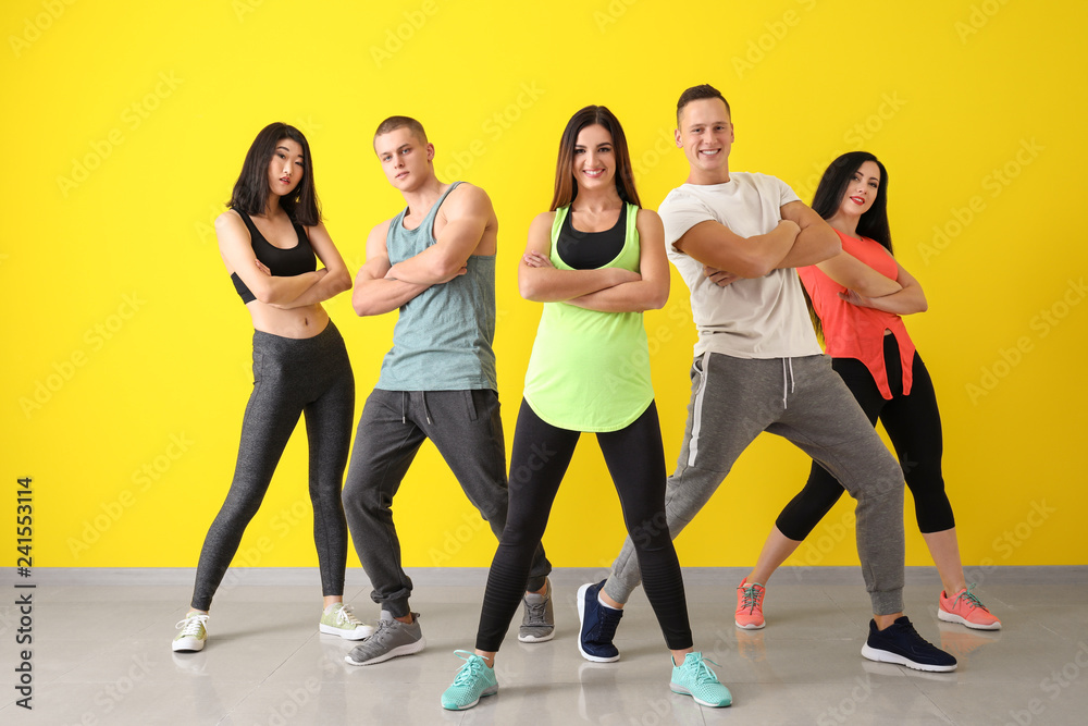 Fototapeta premium Team of young dancers near color wall