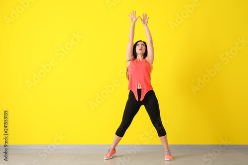 Young woman dancing near color wall