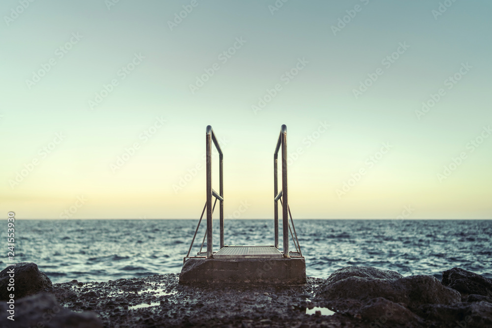 Fototapeta premium Pier out to the ocean on the beach with stones.