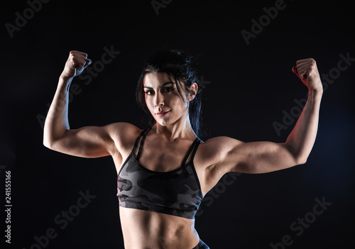 Sporty muscular woman on dark background