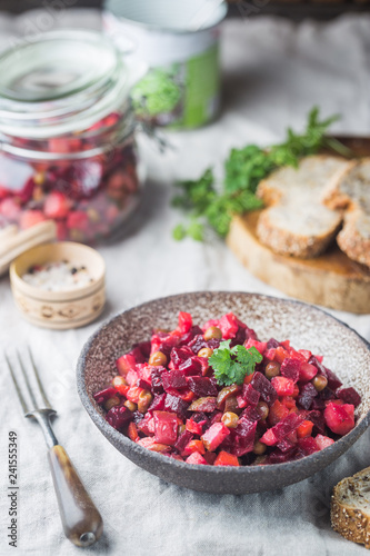 Russian beetroot salad vinaigrette in a bowl with rye bread, rustic background