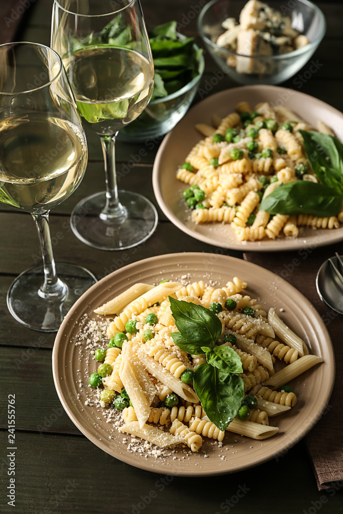Plates with tasty pasta and green peas on wooden table