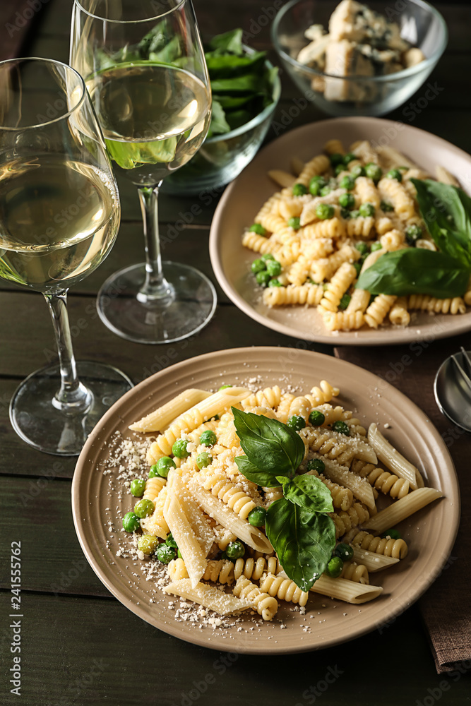 Plates with tasty pasta and green peas on wooden table Plates with tasty pasta and green peas on wooden table