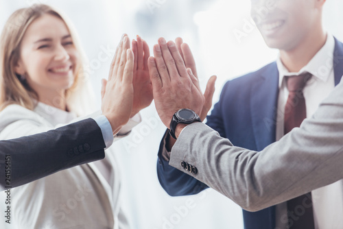 cropped shot of professional successful business team giving high five in office