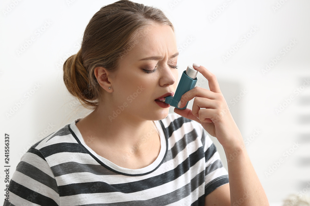Young woman with inhaler having asthma attack at home Young woman with inhaler having asthma attack at home