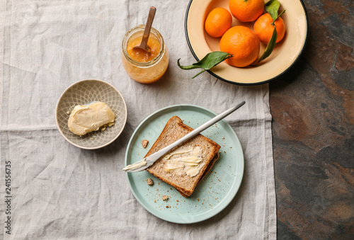 Bread with butter and tasty tangerine jam on table