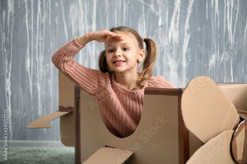 Fototapeta Naklejka Na Ścianę i Meble -  Little girl playing with cardboard airplane in room