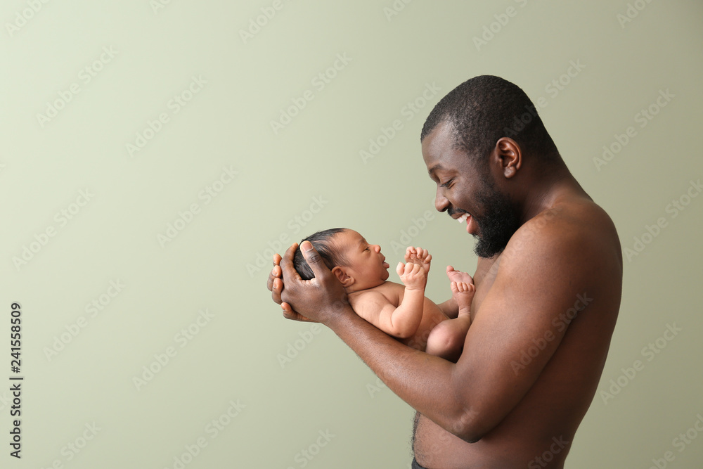 Naklejka premium Portrait of happy African-American father with little baby on color background