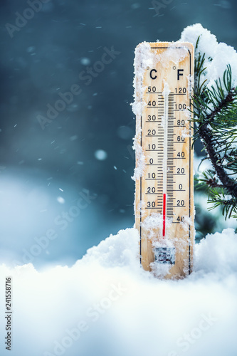 Thermometer on snow shows low temperatures in celsius or farenheit photo