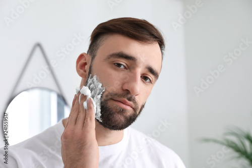 Handsome man applying shavi...
