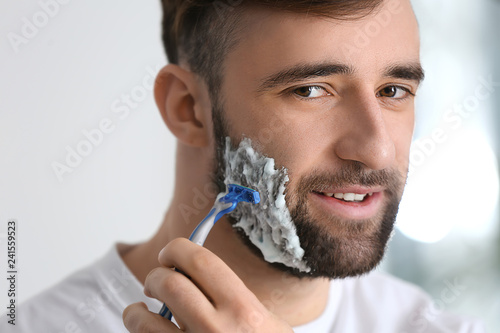 Handsome man shaving in bat...
