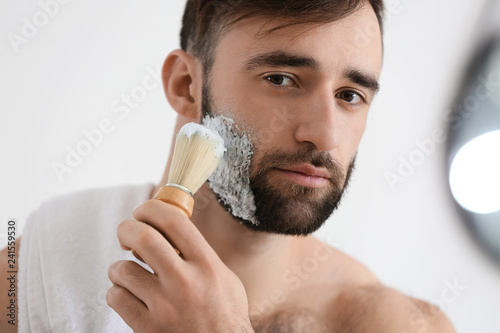 Handsome man shaving in bat...