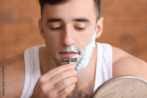 Handsome man shaving in bat...