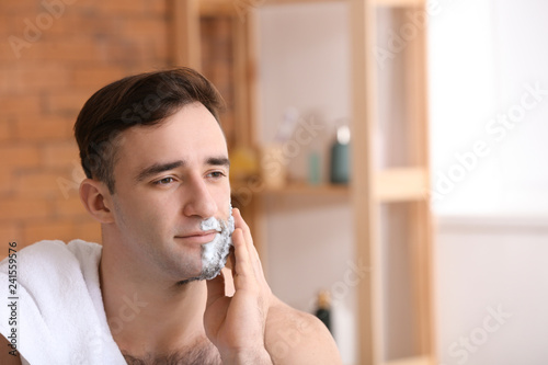 Handsome man shaving in bat...