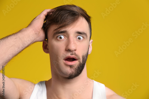 Shocked man having half of his face shaved against color background