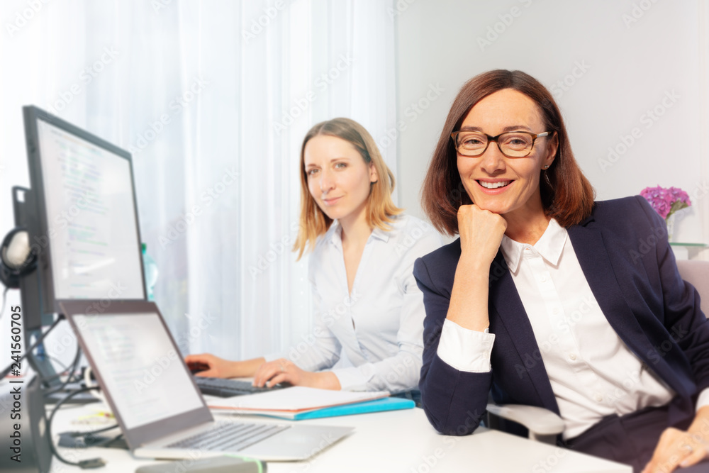 Businesswoman and assistant sitting at office desk Businesswoman and assistant sitting at office desk