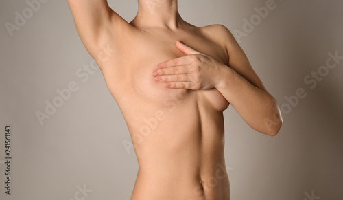 Naked woman on grey background. Concept of breast augmentation photo