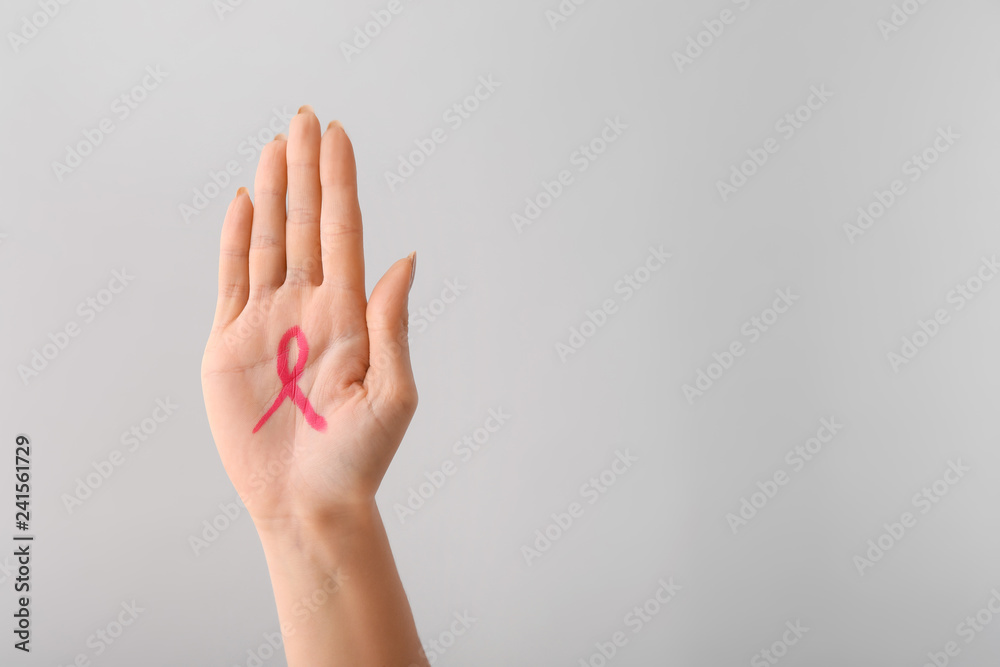 Woman with pink ribbon drawn on her palm against light background. Breast cancer awareness concept Woman with pink ribbon drawn on her palm against light background. Breast cancer awareness concept