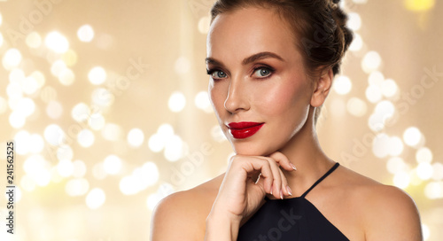 people, luxury and beauty concept - close up of beautiful woman in black with red lipstick over beige background and festive lights © Syda Productions