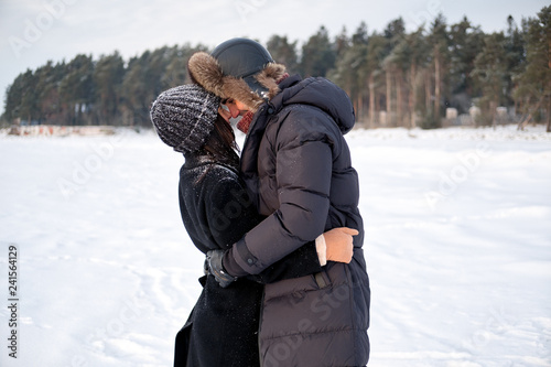Young millennial couple in love embracing in winter park outdoor. Sensual tender boyfriend and girlfriend enjoying romantic moment together, feeling intimacy and closeness.