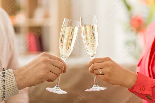 valentines day, celebration and engagement concept - close up of couple hands clinking champagne glasses